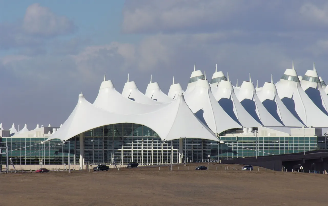 The white tent-roof peaks of the terminal at Denver International Airport under a partly cloudy sky