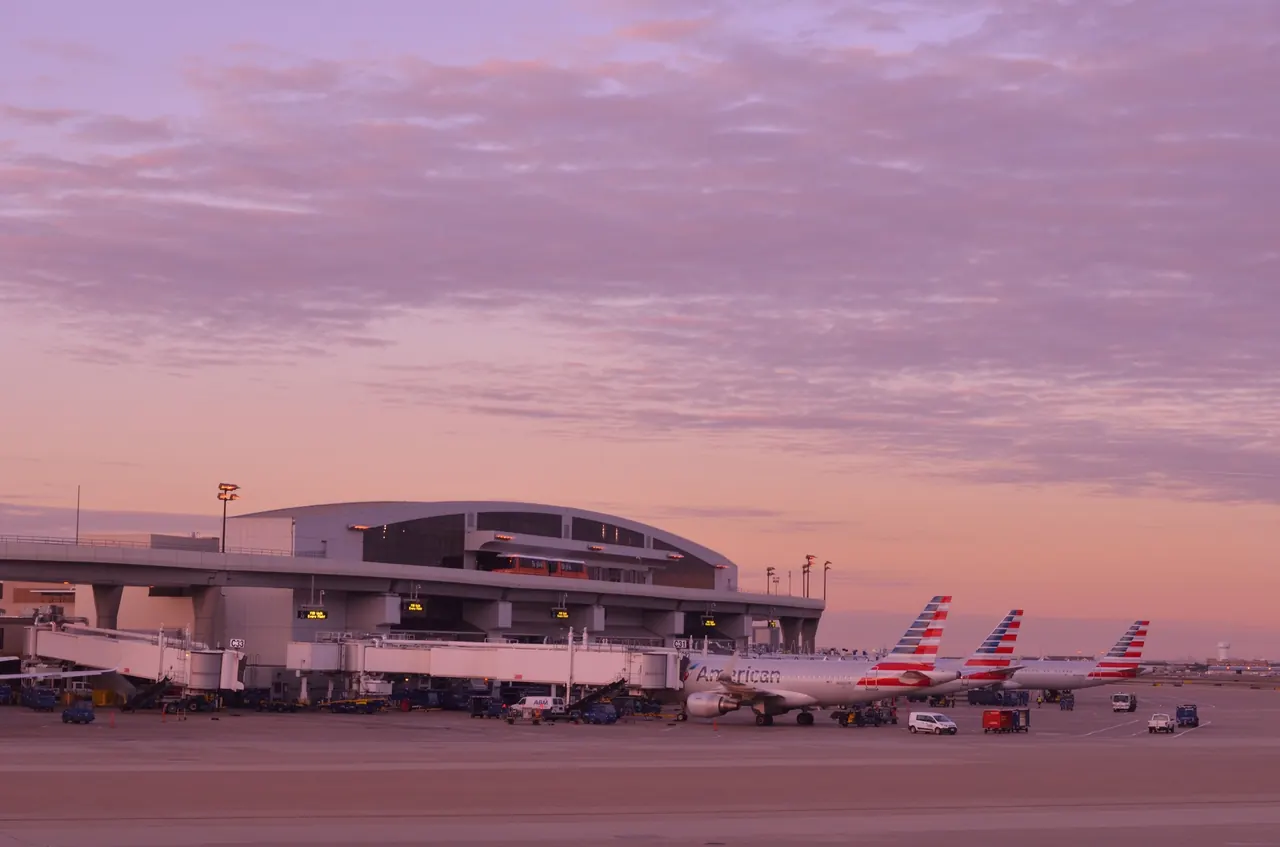 American Airlines jets parked at the gates of a terminal at Dallas Fort Worth International Airport at dusk
