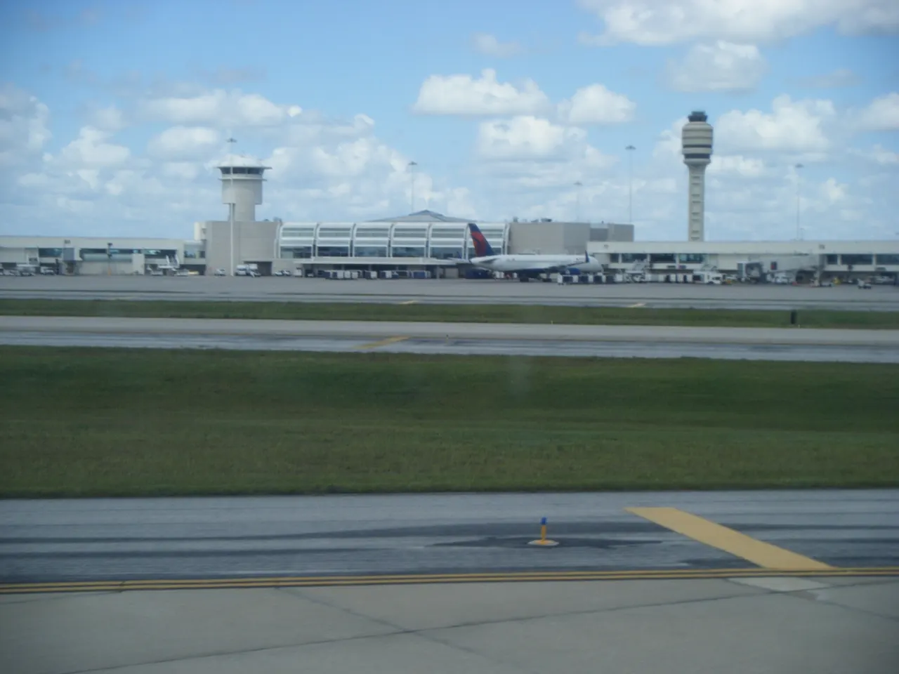 The Orlando International Airport terminal and two control towers seen across the airfield from an arriving aircraft
