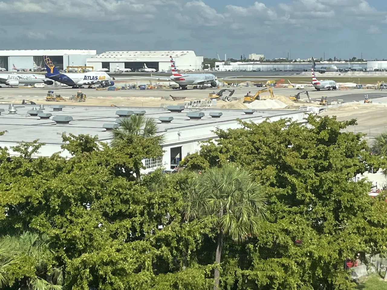 Cargo and passenger aircraft on the apron at Miami International Airport, seen over palm trees from the MIA Mover
