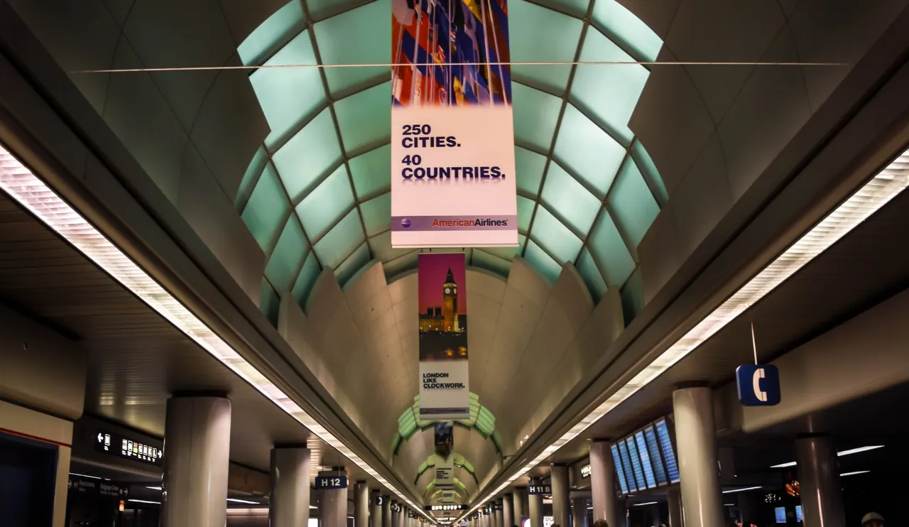 Travelers walking down Concourse H in Terminal 3 at Chicago O'Hare under a glass-panelled ceiling