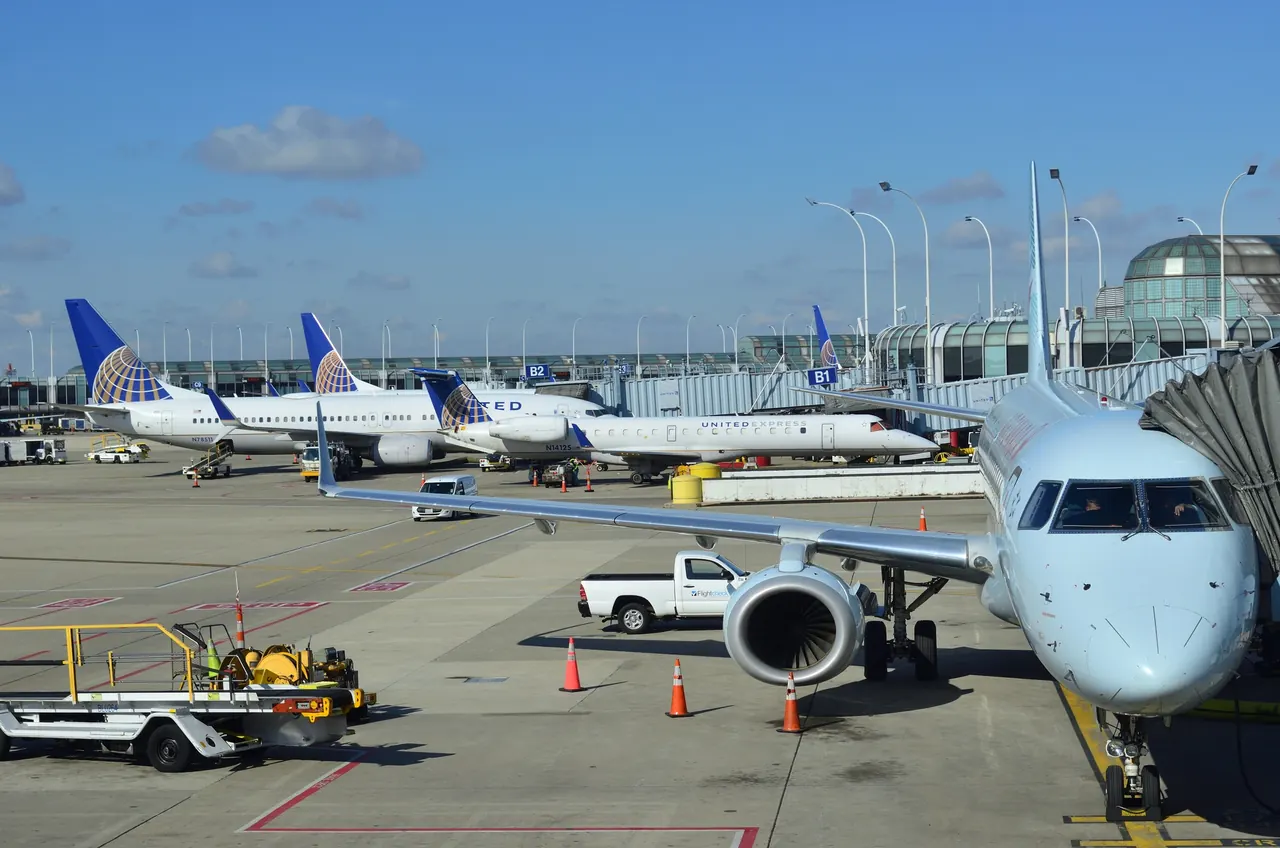 A regional jet at a gate at Chicago O'Hare International Airport with United Airlines aircraft parked beyond it