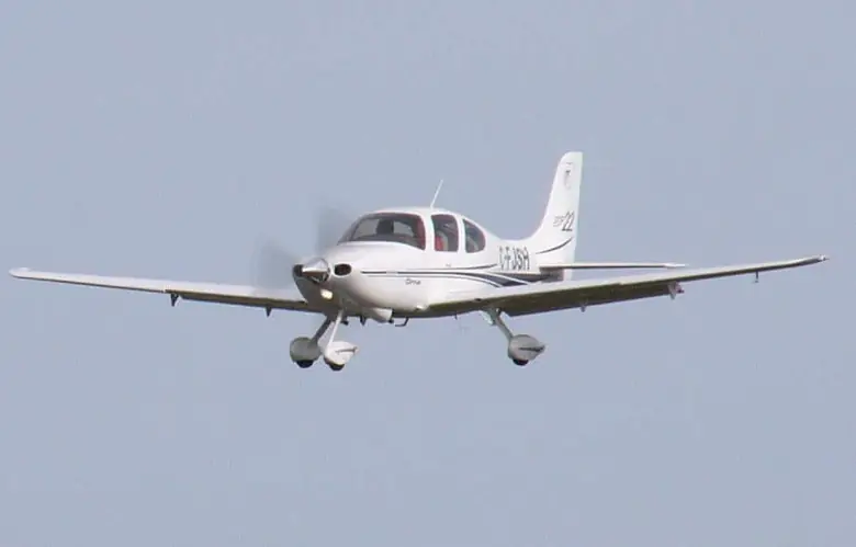 Cirrus SR22 flying straight toward the camera against a pale blue sky