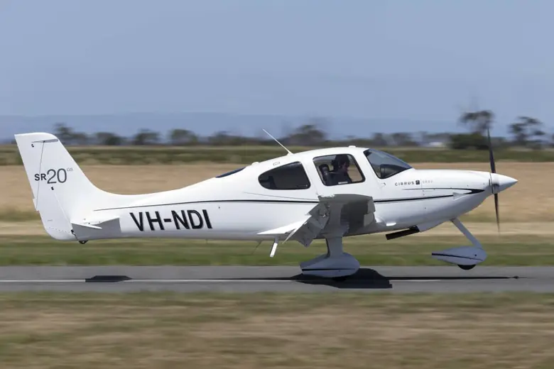 White Cirrus SR20 flying low above a runway
