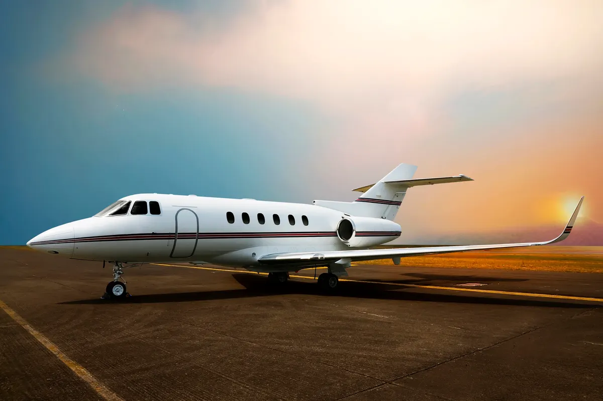 A private jet parked on an airport ramp in evening light
