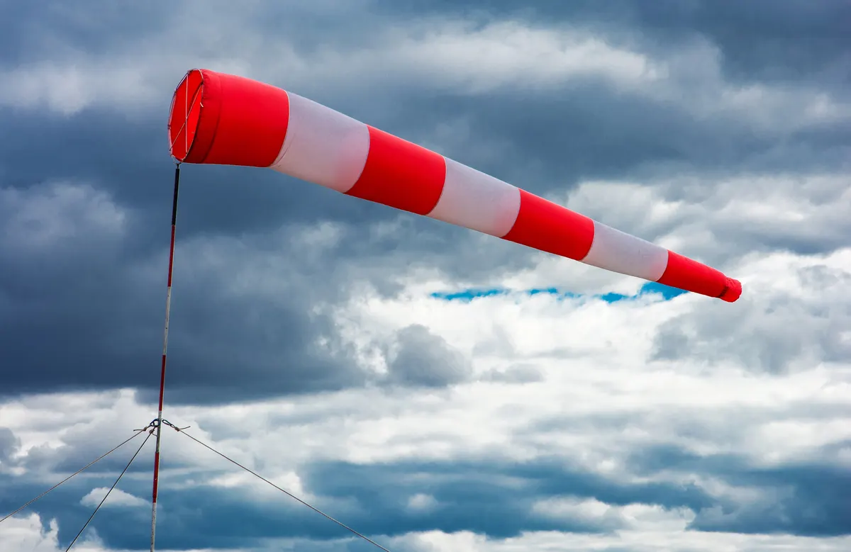 A red and white windsock against dark storm clouds