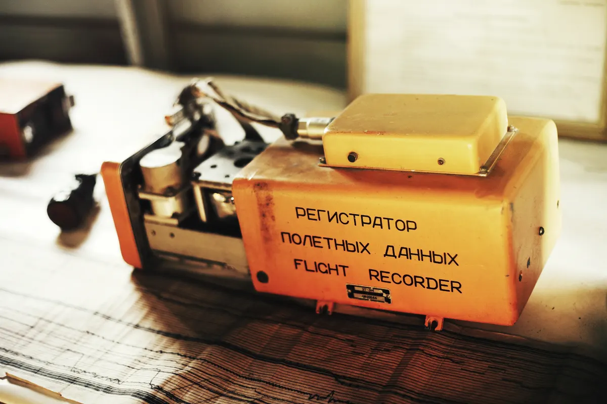 An orange flight data recorder with its cover open on a table