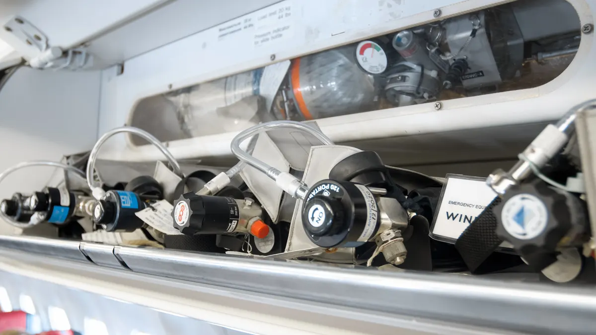 Pressure valves and gauges on emergency oxygen cylinders inside a jet aircraft